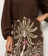 Vestido midi de viscosa con estampado de follaje, escote cuadrado y mangas largas con puños elásticos. Presenta un corte evasé y un lazo fino en la cintura.