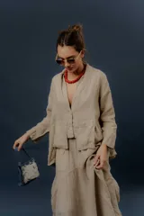 Chaqueta de lino color beige, de calce relajado, con escote en V, cierre frontal con botones y bolsillos frontales aplicados.
