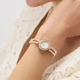 Reloj analógico Guess modelo Cassidy con caja y malla de acero inoxidable en tono oro rosa. Presenta una esfera plateada con acabado sunray y un bisel decorado con cristales brillantes. El diseño de la malla es tipo brazalete con eslabones texturizados.