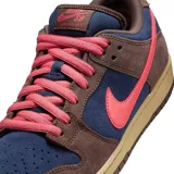 Championes Nike SB Dunk Low con diseño de paneles en gamuza azul marino y marrón, acentuados con un swoosh y cordones en color rosa vibrante, sobre una suela de goma en tono caramelo.