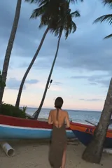 Vestido midi de tejido de punto con acabado brillante, diseño halter con espalda descubierta y detalle de piedras de resina en el cuello. Presenta un tajo lateral pronunciado.