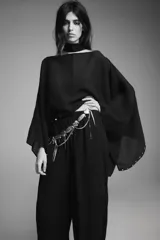 Capa negra de cuello redondo con detalle de tachas plateadas en el ruedo y pañuelo tipo bufanda integrado en el mismo tejido.