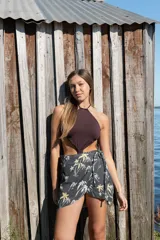 Falda tipo pareo corta con estampado de palmeras, diseño cruzado con lazo lateral para ajustar.