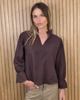 Blusa de algodón color marrón, con escote en V, cuello con volados y mangas largas abullonadas con puños elastizados.