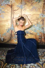 Vestido largo strapless de encaje negro con transparencias y espalda descubierta con tiras cruzadas, de corte entallado y falda de caída suelta.