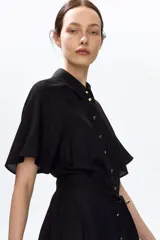 Vestido midi negro con cuello camisero, botonadura frontal de botones dorados, mangas cortas y cinturón ajustable para atar en la cintura.