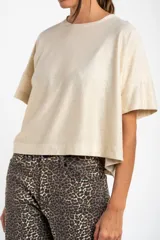 Remera color crema con brillo, de corte amplio y mangas cortas.