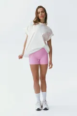 Remera deportiva de punto de algodón color blanco, de corte oversized con mangas cortas, hombros caídos y cuello redondo ribeteado. Presenta un estampado frontal en relieve dentro de un óvalo.