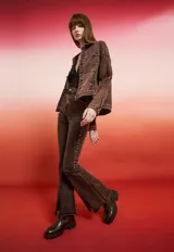 Campera de jean con lavado oscuro rojizo/marrón, estilo trucker. Presenta tachas doradas a lo largo de los bordes de los bolsillos, el canesú y los puños. Posee un bordado en relieve de diseño floral en la manga.