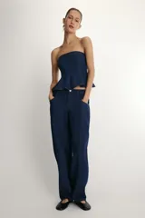 Pantalón de jean azul oscuro con corte tipo ballon, tiro alto, cierre frontal con cremallera y botón metálico, bolsillos delanteros y traseros.