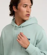 Hoodie de algodón y poliéster color verde menta, con capucha ajustable con cordón y bolsillo canguro frontal. Presenta un pequeño logo bordado en el pecho izquierdo con el texto "Urban Chill".