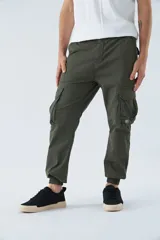 Pantalón cargo color beige, corte slim, con bolsillos laterales con botón, cierre con botón y puños en los tobillos.