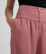 Pantalón rosado de liocel con cintura ancha y pespuntes, cierre frontal con cremallera, dos bolsillos laterales y bajo diagonal.
