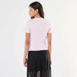 Camiseta rosa de punto de canalé fino con cuello redondo y corte ajustado. Presenta una abertura en el bajo. 