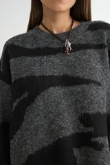 Buzo de punto con diseño estampado abstracto en blanco y negro, de corte holgado, cuello redondo y mangas largas con puños acanalados.