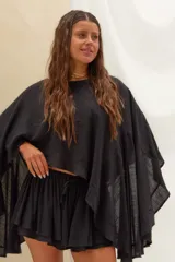 Set de blusa estilo capa de corte holgado con mangas amplias y short con volados y cordón ajustable en la cintura, confeccionado en lino color negro.