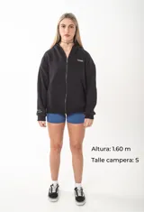 Campera con cierre frontal metálico, confeccionada en algodón pesado de alto gramaje. Presenta un diseño oversize con capucha, bolsillos tipo canguro y bordados minimalistas en el frente y en la manga.