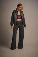 Chaqueta oversize de cuero sintético texturado color negro, con acceso por cartera central con broches, bolsillos laterales y superiores en frente y cintura elastizada.