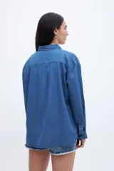 Camisa de denim azul de algodón, con cuello solapa, calce relaxed, manga larga y bolsillo cuadrado en el pecho. Cierre frontal con botones personalizados.
