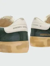 Championes de gamuza color verde oscuro con suela de goma envejecida, cordones blancos y detalle de talón en cuero blanco.