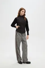 Chaleco negro con diseño capitoneado, cierre frontal con botones a presión y cuello alto.