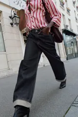 Camisa de cuello solapa con estampado de rayas verticales en tonos rojos, rosas y blancos. Presenta cierre frontal con botones y mangas tres cuartos con puño vuelto.