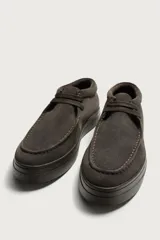 Zapato de cordones de estilo casual, confeccionado en piel con acabado en serraje de color marrón. Presenta detalle de bordón en el empeine, horma redonda y suela de goma a contraste.