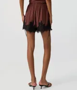Short marrón de viscosa con calce suelto, cintura elástica y detalle de encaje floral negro en el ruedo. Cuenta con amarras laterales ajustables.