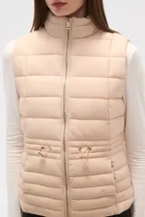 Chaleco acolchado negro, sin mangas, con cuello alto y cierre frontal con cremallera dorada. Presenta cordones ajustables a la altura de la cintura.