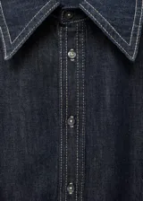 Camisa de denim oscuro con costuras en contraste, cuello camisero clásico, cierre frontal con botones y mangas largas con puños abotonados.