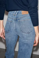 Jeans mom fit de tiro alto y diseño tobillero, confeccionados en denim de lavado medio con cinco bolsillos, trabillas para cinturón y cierre frontal con cremallera y botón metálico.