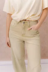 Jean de calce relajado y pierna amplia color beige, con tiro alto y detalle de recortes y costuras visibles.