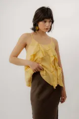 Musculosa de lino color amarillo, con tirantes finos, escote redondo y detalle de volados frontales.
