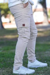 Pantalón cargo beige de corte ajustado, con bolsillos laterales tipo cargo en las piernas y detalle de etiqueta de cuerina en el bolsillo derecho.
