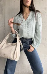 Camisa celeste con bordados florales, cuello en V y cierre frontal con botones.