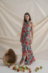 Vestido largo de gasa de seda natural con estampado floral en tonos verde y rojo. Tiene corte en la cintura, falda con volados y tajo delantero.