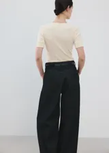 Camiseta de punto de algodón en color beige claro, con cuello redondo y mangas cortas. Diseño ajustado y estilo minimalista.