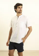 Camisa de manga corta con cuello mao y cierre frontal parcial con botones de coco. Presenta un bolsillo frontal en el pecho y un diseño de corte recto.
