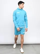 Campera deportiva Umbro de piqué, color celeste, con capucha, cierre frontal completo y detalles de piping en las mangas.