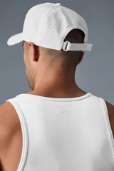 Gorra tipo trucker blanca con corona estructurada y paneles traseros perforados para mayor ventilación. Presenta el logo de la marca bordado en relieve al tono en el frente y cierre ajustable con velcro.