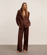 Pantalón wide leg de sastrería y cintura alta en color marrón, confeccionado en mezcla de viscosa y lino, con pliegues frontales y trabillas para cinturón.