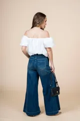 Blusa blanca con escote elástico que permite usarla con hombros descubiertos o más alta.