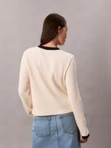 Remera de manga larga Calvin Klein confeccionada en tejido waffle de color beige, con cuello redondo y puños en contraste de color negro. Presenta un pequeño parche con el logo de la marca en el lateral inferior.