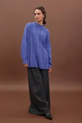 Sweater de punto negro con diseño de trenzas verticales, cuello alto y corte holgado de estilo oversize.