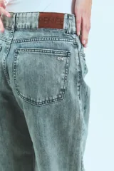 Jean de corte oversize con tiro medio-alto, confeccionado en denim de algodón con lavado tipo ice wash en tono grisáceo. Presenta diseño de cinco bolsillos, cierre frontal y etiqueta de cuero en la parte posterior de la cintura.