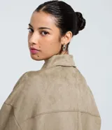 Camisa de corte regular confeccionada en gamuza sintética color beige, con cuello inglés, cierre frontal abotonado, mangas largas con puños ajustados y bolsillo tipo cargo en el pecho.