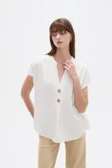 Blusa de viscosa color blanco, de corte holgado, con cuello en V y cierre frontal parcial de botones grandes con efecto carey.