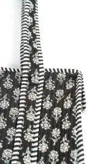 Bolso tipo tote acolchado, con diseño estampado de flores y tallos sobre fondo bordó, y asas con detalles a rayas.