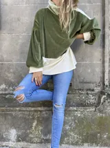 Polerón de corte holgado con mangas largas abullonadas, confeccionado en terciopelo negro con detalles en beige y blanco.