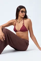 Top de bikini negro confeccionado en tejido con textura, de diseño triangular y detalle de aros cuadrados en los breteles. Se ajusta en cuello y espalda con lazos finos.